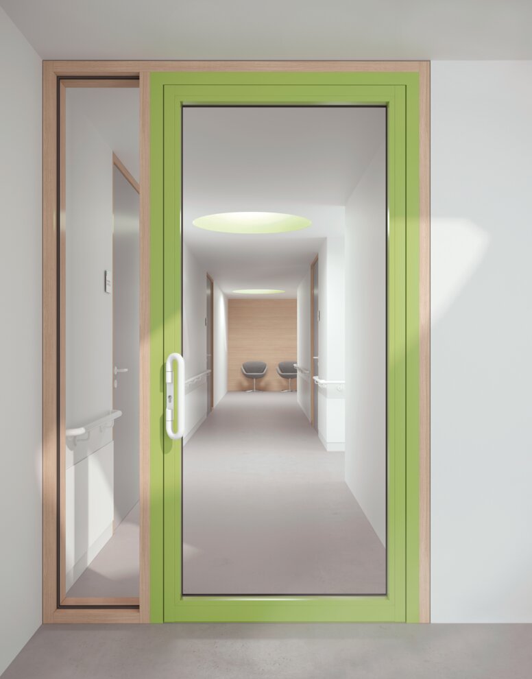 Glazed hospital door with green frame equipped with a lever handle in the colour signal white made of polyamide