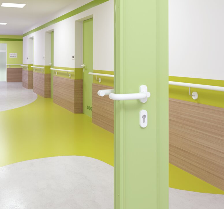 Glazed hospital door with green frame equipped with a door handle in the colour signal white made of polyamide